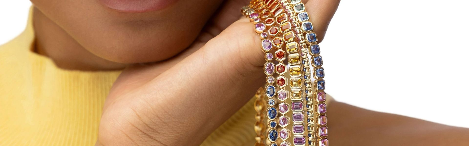 Close-up of a hand holding colorful gemstone necklaces by Elyzian Jewelry.
