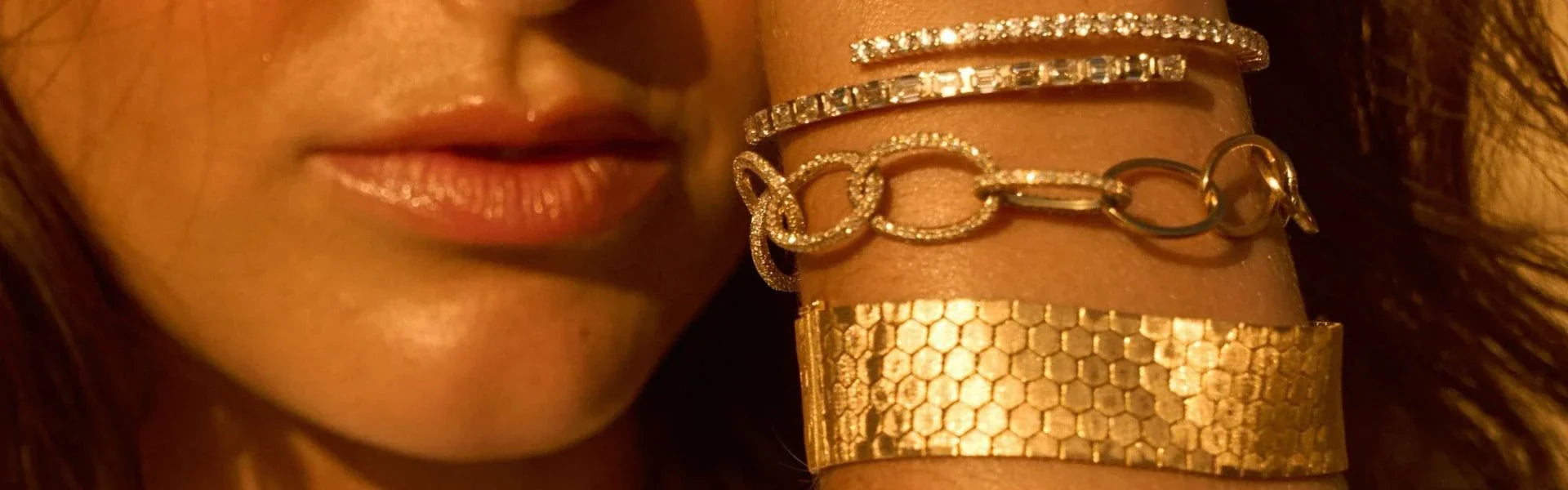 Woman wearing stacked gold jewelry including textured gold cuff bracelet, diamond bypass bangles, and chain link bracelet from Elyzian's Timeless Gold Collection