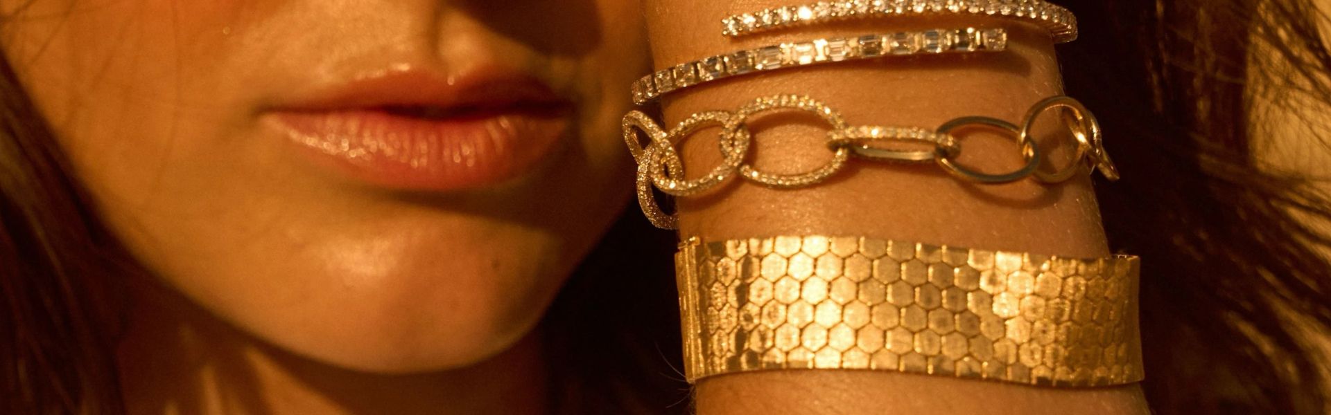 Gold tennis bracelets and textured cuff stacked on wrist, luxury fine jewelry arm candy collection by Elyzian Jewelry