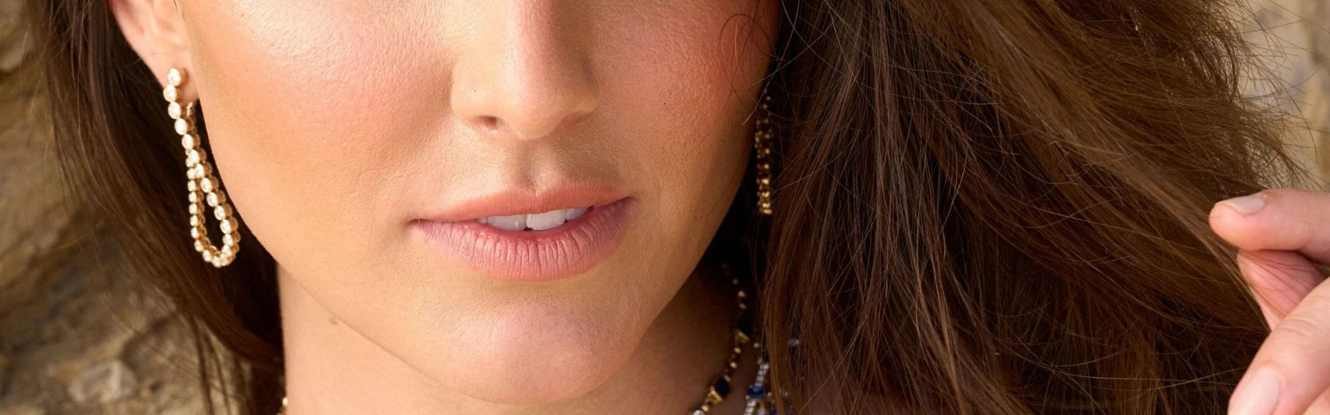 Close-up of a woman's face with statement earrings and necklace by Elyzian Jewelry