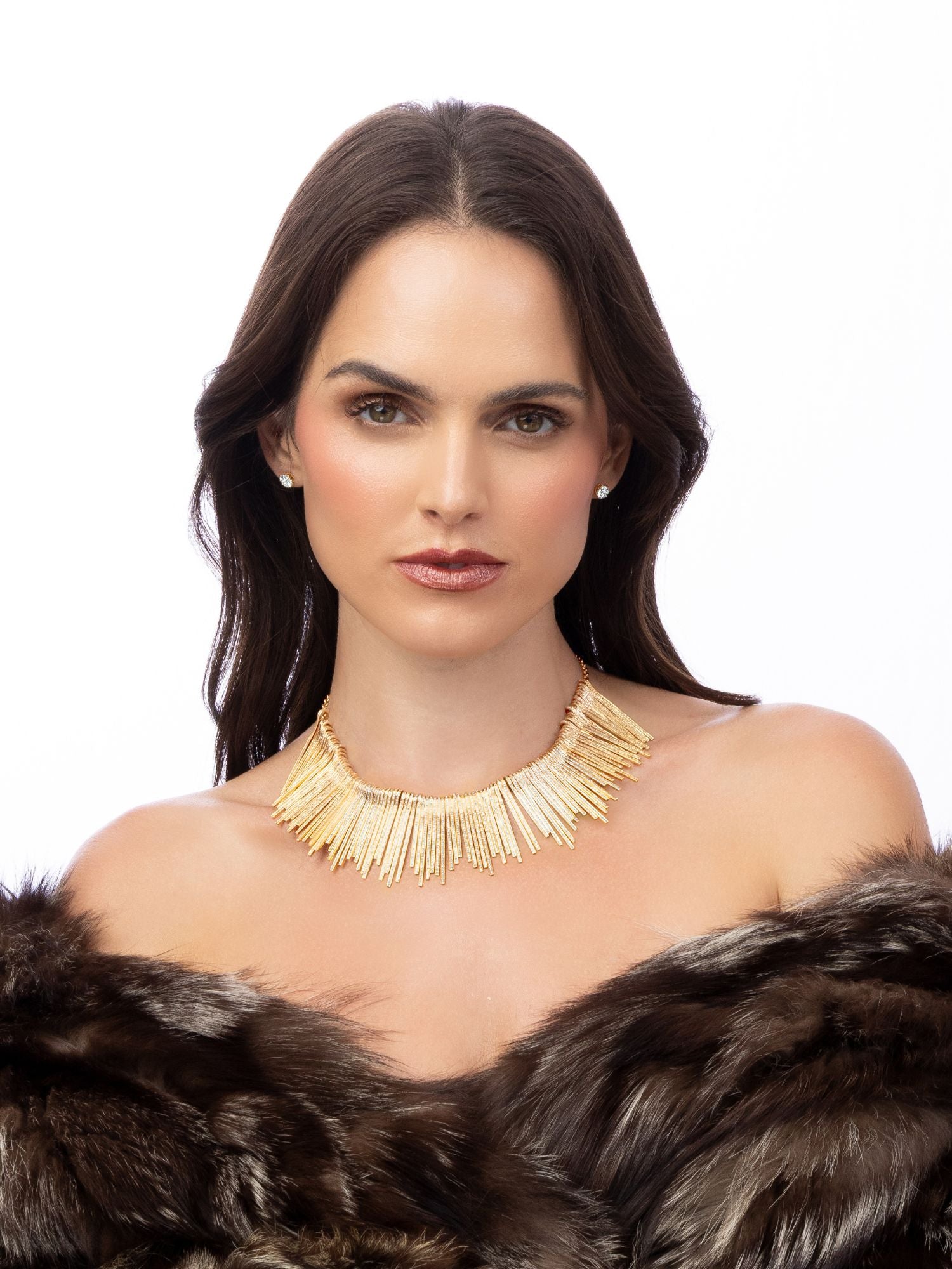 Woman wearing a gold necklace and fur coat on a white background