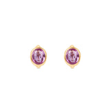Enchanting pink sapphire huggie earrings crafted in 14K yellow gold, featuring vibrant oval-cut pink sapphires for a perfect blend of charm and sophistication, suitable for any occasion. Front view, close up. 