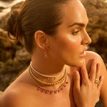 Gold bead necklace featuring diamond and pink sapphire accents, shown worn around the neck.