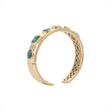 Exquisite 14K yellow gold bangle featuring seven bezel-set emeralds in mixed shapes totaling 10 carats, creating a bold yet refined statement of elegance and color.