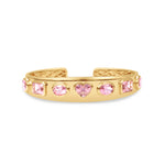 Exquisite 14K yellow gold bangle featuring seven mixed-shape pink tourmalines, including oval, cushion, and heart shapes, blending sophistication with playful charm for a luxurious statement piece. Close up of front. 