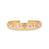 Exquisite 14K yellow gold bangle featuring seven mixed-shape pink tourmalines, including oval, cushion, and heart shapes, blending sophistication with playful charm for a luxurious statement piece. Close up of front. 