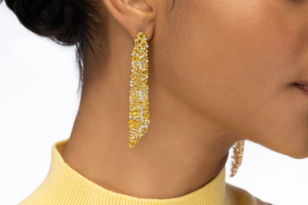 Statement 14K yellow gold earrings featuring hand-selected yellow sapphires and brilliant diamonds, radiating warmth and elegance inspired by the golden glow of sunlight. On model. 