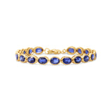 Luxurious 14K gold tennis bracelet featuring bezel-set oval-cut blue sapphires, exuding timeless elegance and vibrant sophistication.