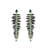 One-of-a-kind 14K yellow gold feather earrings featuring black onyx, emeralds, and diamonds, uniquely designed for versatility—wear as dramatic dangle earrings or convert into a striking feather bracelet paired with emerald studs. Shown as earrings. 