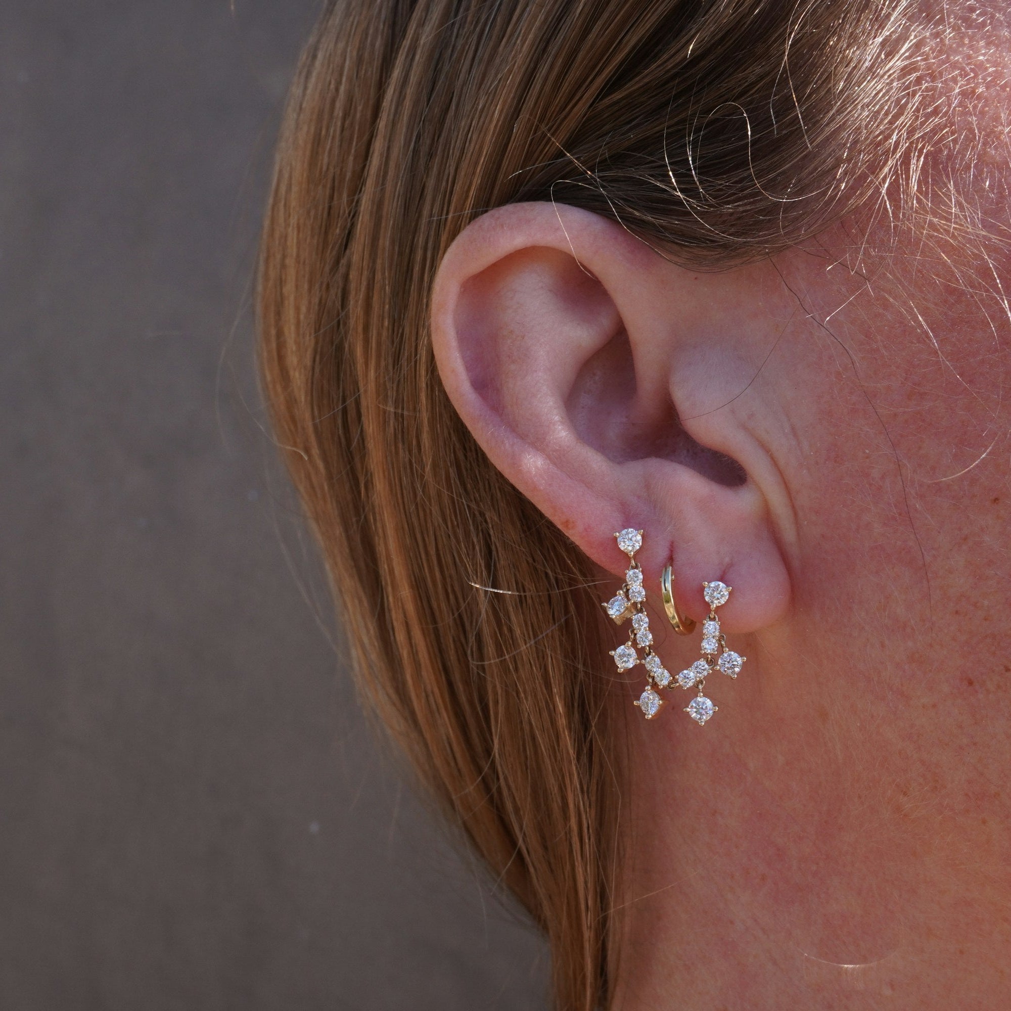 14K yellow gold double piercing drop stud earrings featuring cascading round diamonds, offering a dazzling effect with graceful movement, blending contemporary style with timeless elegance. on Model. 