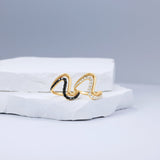 Striking 14K yellow gold wave ring featuring a bold double-wave design, accented with captivating black diamonds and sleek black rhodium details for modern elegance. Displayed with the white diamonds. 