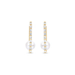 Stunning elongated hoop earrings featuring a sleek rectangular design adorned with diamond baguettes along the outside and a beautiful pearl solitaire at the bottom, crafted in 14K gold for a sophisticated statement. Front view. 