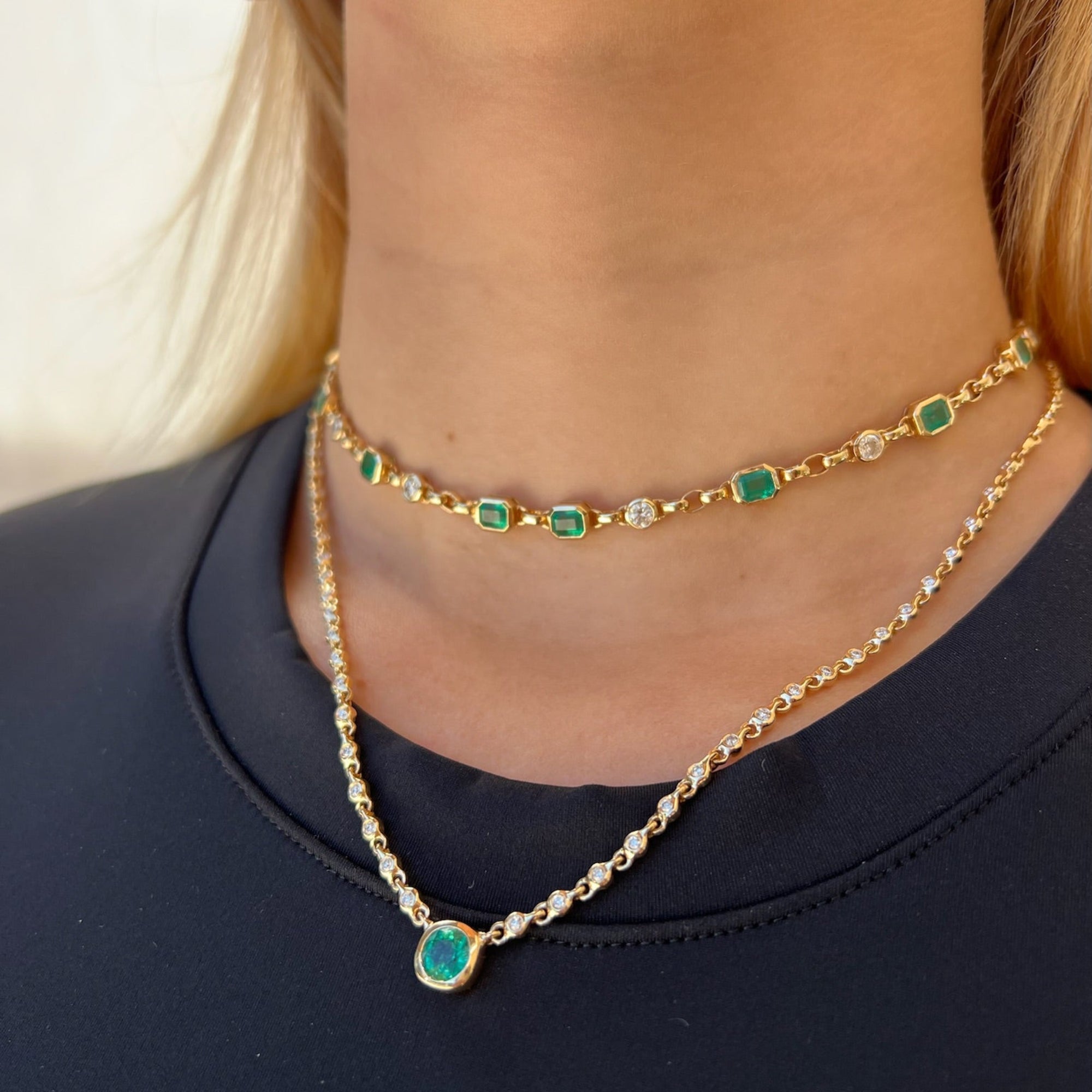 Elegant 14K yellow gold necklace featuring a 1ct bezel-set emerald solitaire pendant on a mini rolo chain with 0.58ct of diamond accents and an adjustable 16–18 inch length.