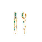 Captivating double hoop earrings featuring shimmering diamonds and vibrant emeralds in a double huggie design, accentuated by delicate dangling chains for a blend of classic sophistication and modern allure. Front and side view. 