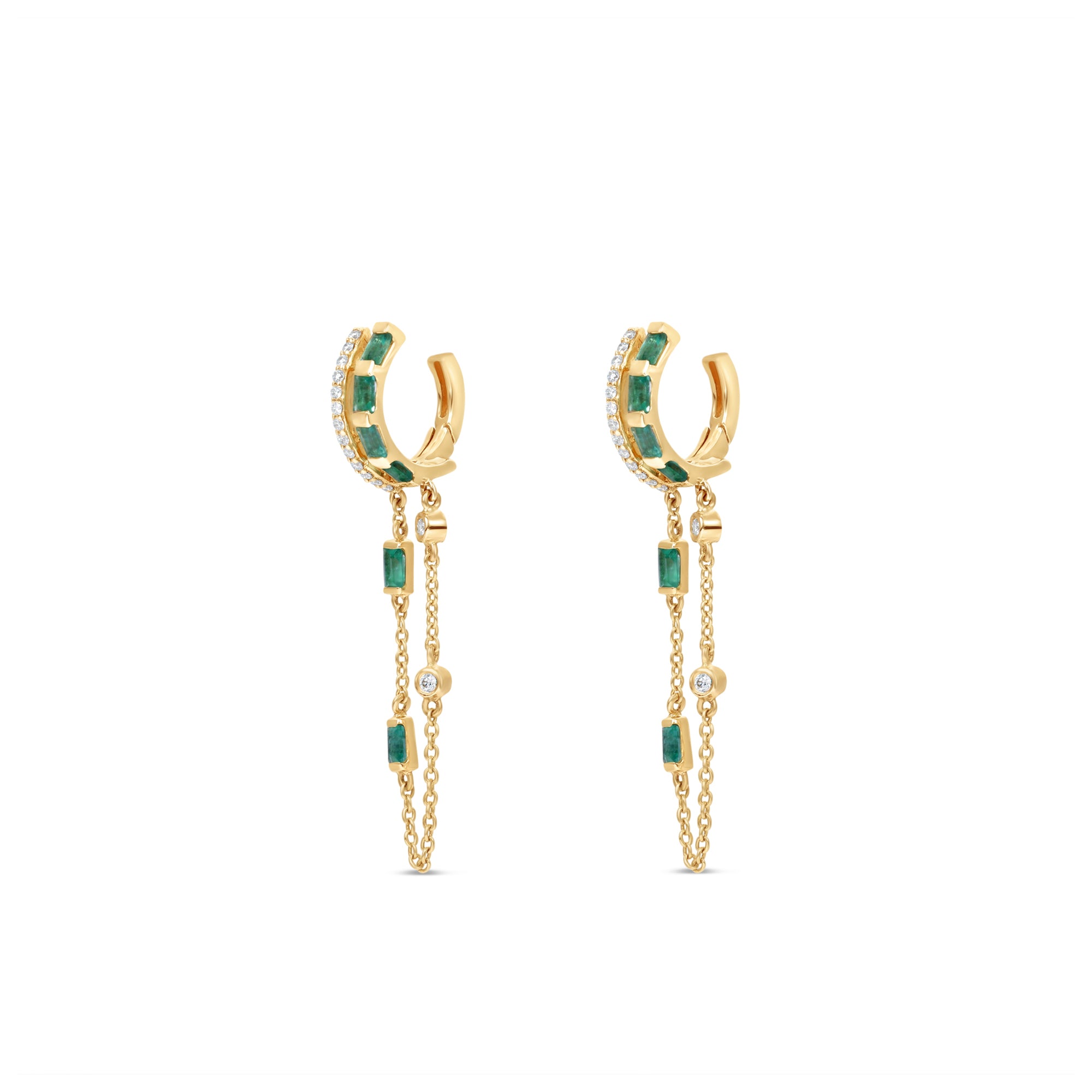 Captivating double hoop earrings featuring shimmering diamonds and vibrant emeralds in a double huggie design, accentuated by delicate dangling chains for a blend of classic sophistication and modern allure. Side view, close up.