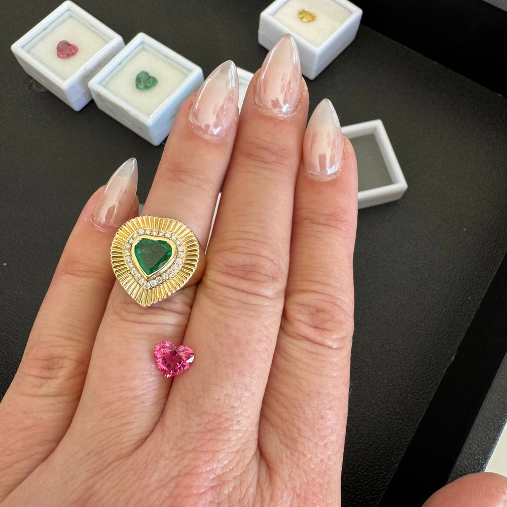 Handcrafted in 14K yellow gold, the softly fluted band creates a dimensional backdrop for a 1.18ct faceted emerald heart, prized for its vivid green hue. A halo of 25 pavé-set diamonds (0.22ct, F–G VS) encircles the center stone, adding a brilliant frame that enhances its natural beauty. Designed with a low-profile setting for effortless wear, the ring combines timeless romance with modern edge—perfect for marking life’s most meaningful moments or as a signature everyday piece.