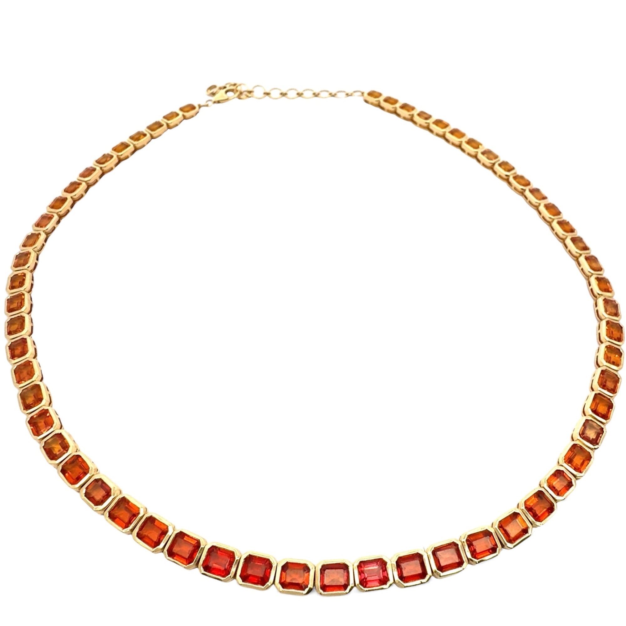 Stunning one-of-a-kind mandarin orange sapphire necklace featuring large east-west set emerald-cut sapphires, elegantly wrapped in 14K yellow gold for a bold and vibrant statement. Close up.