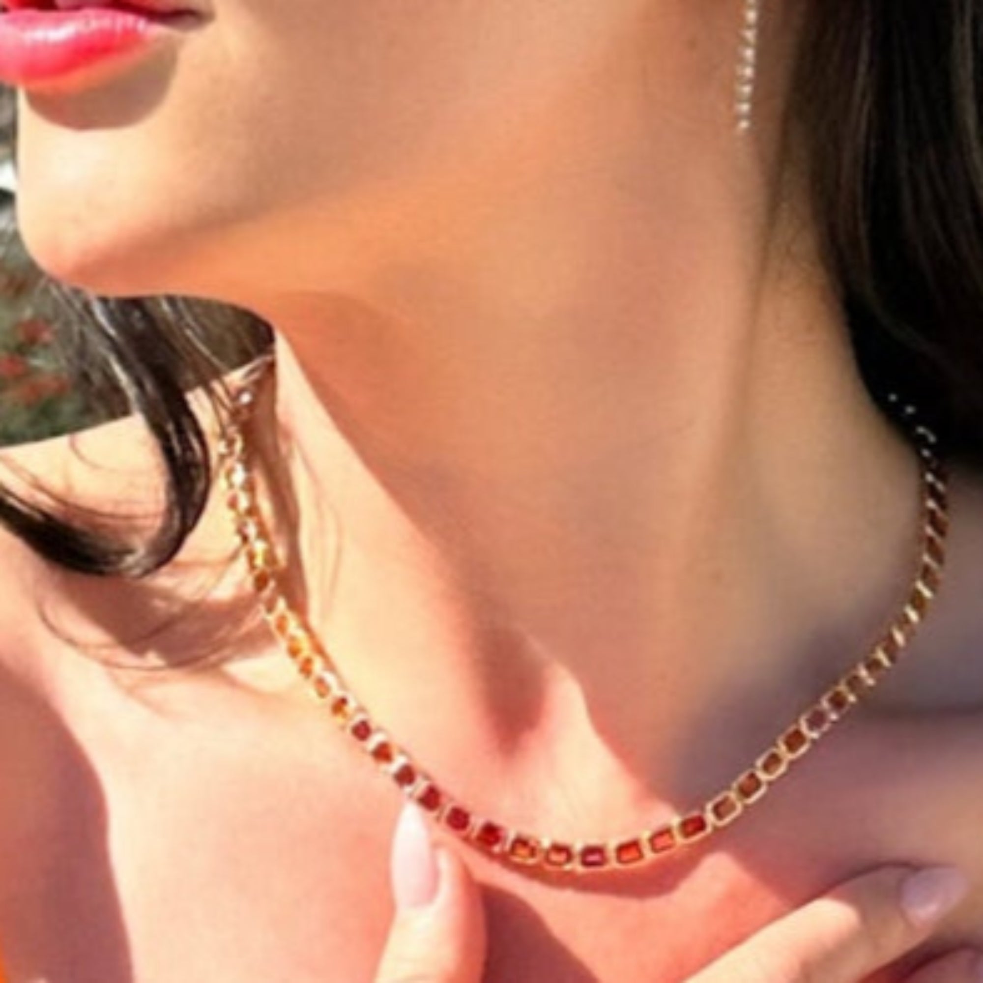 Stunning one-of-a-kind mandarin orange sapphire necklace featuring large east-west set emerald-cut sapphires, elegantly wrapped in 14K yellow gold for a bold and vibrant statement. On model.