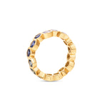 Captivating 18K yellow gold eternity ring featuring vibrant hexagon-cut sapphires in a spectrum of colors, offering a playful yet elegant touch to any jewelry collection. Side angle of gold detail. 