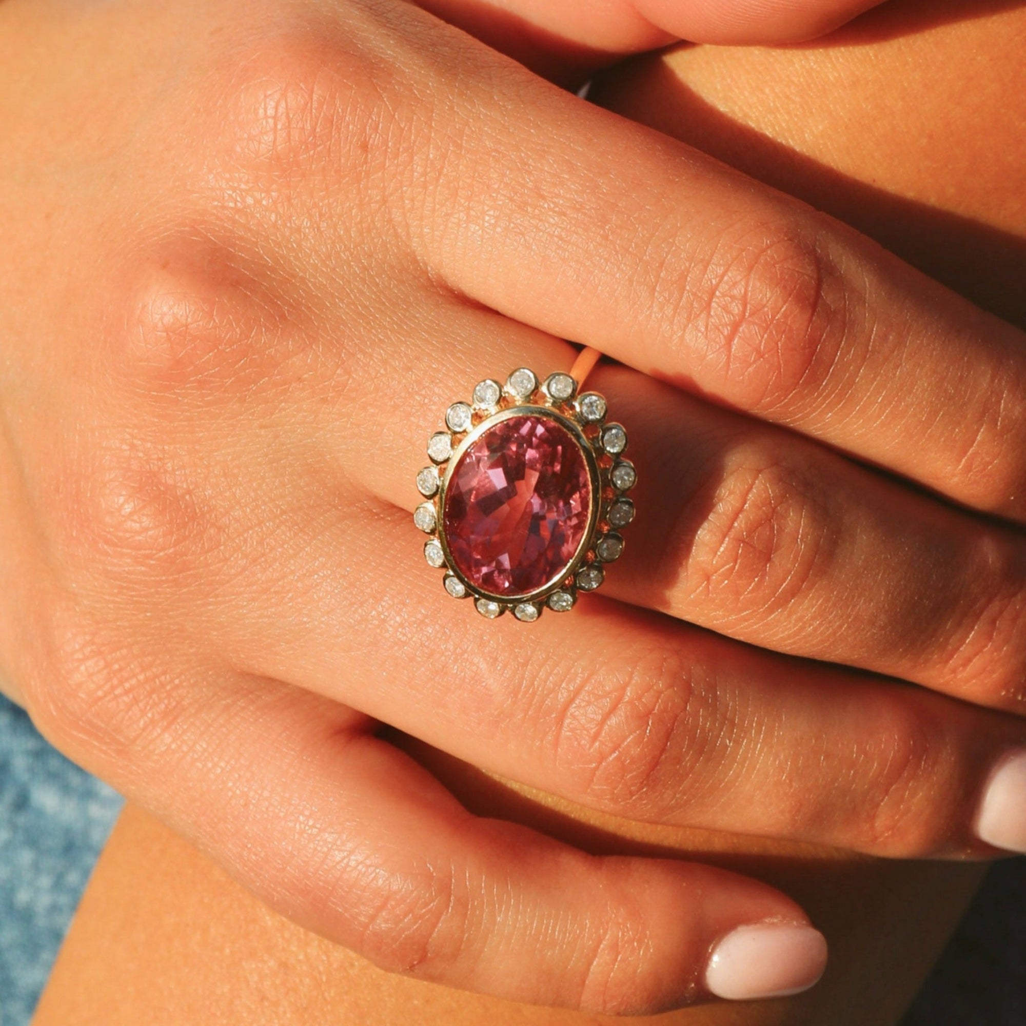 Bold 14K yellow gold cocktail ring featuring a vivid hot pink tourmaline center surrounded by a sparkling diamond halo in an elegant basket setting, designed to make a vibrant statement.