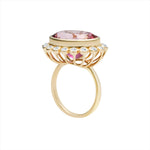 Bold 14K yellow gold cocktail ring featuring a vivid hot pink tourmaline center surrounded by a sparkling diamond halo in an elegant basket setting, designed to make a vibrant statement.