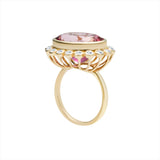 Bold 14K yellow gold cocktail ring featuring a vivid hot pink tourmaline center surrounded by a sparkling diamond halo in an elegant basket setting, designed to make a vibrant statement.