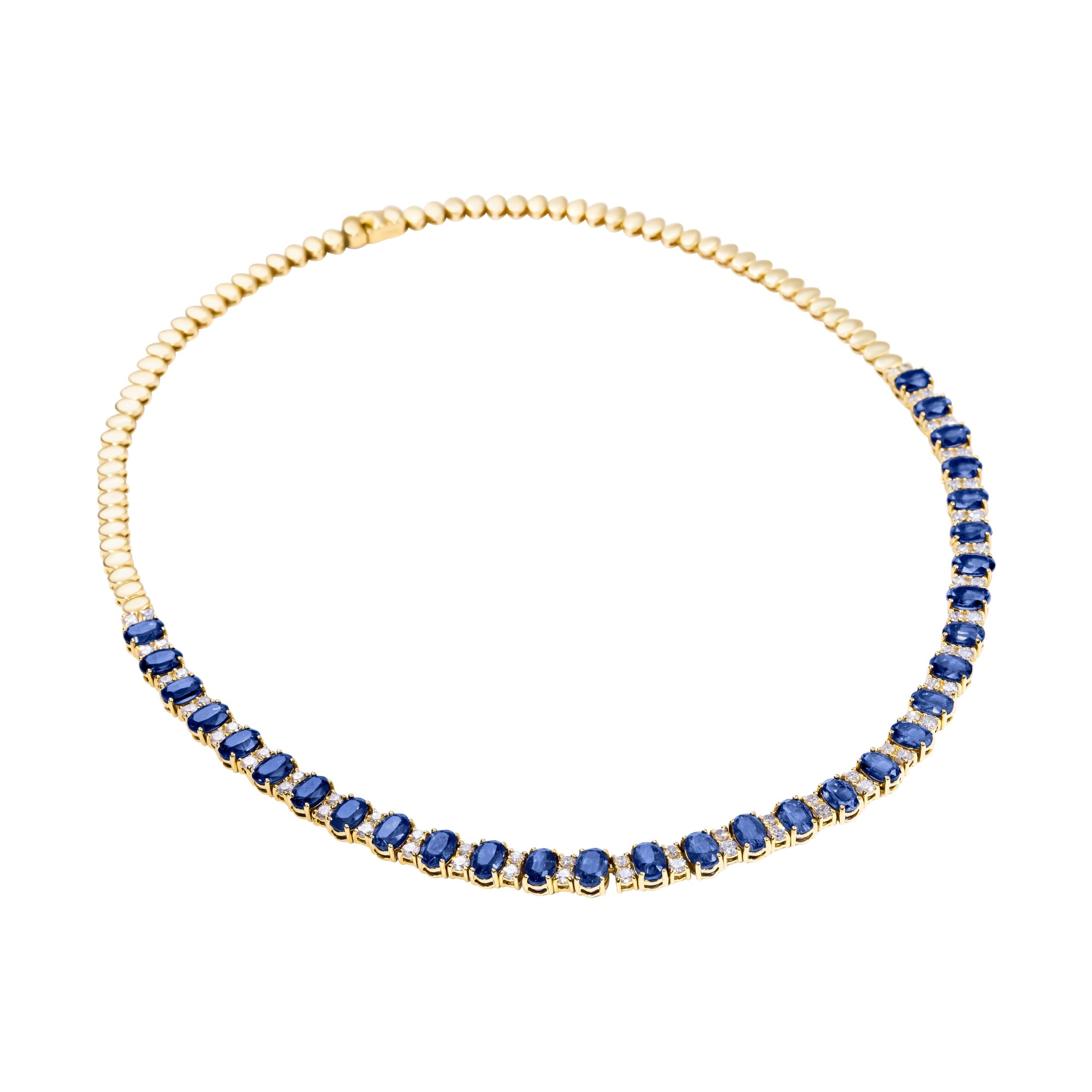 Stunning 14K yellow gold tennis necklace featuring 15.5ct of royal blue oval sapphires and 64 round 2.5mm solitaire diamonds, totaling 16 inches in length—a timeless and regal gemstone piece.