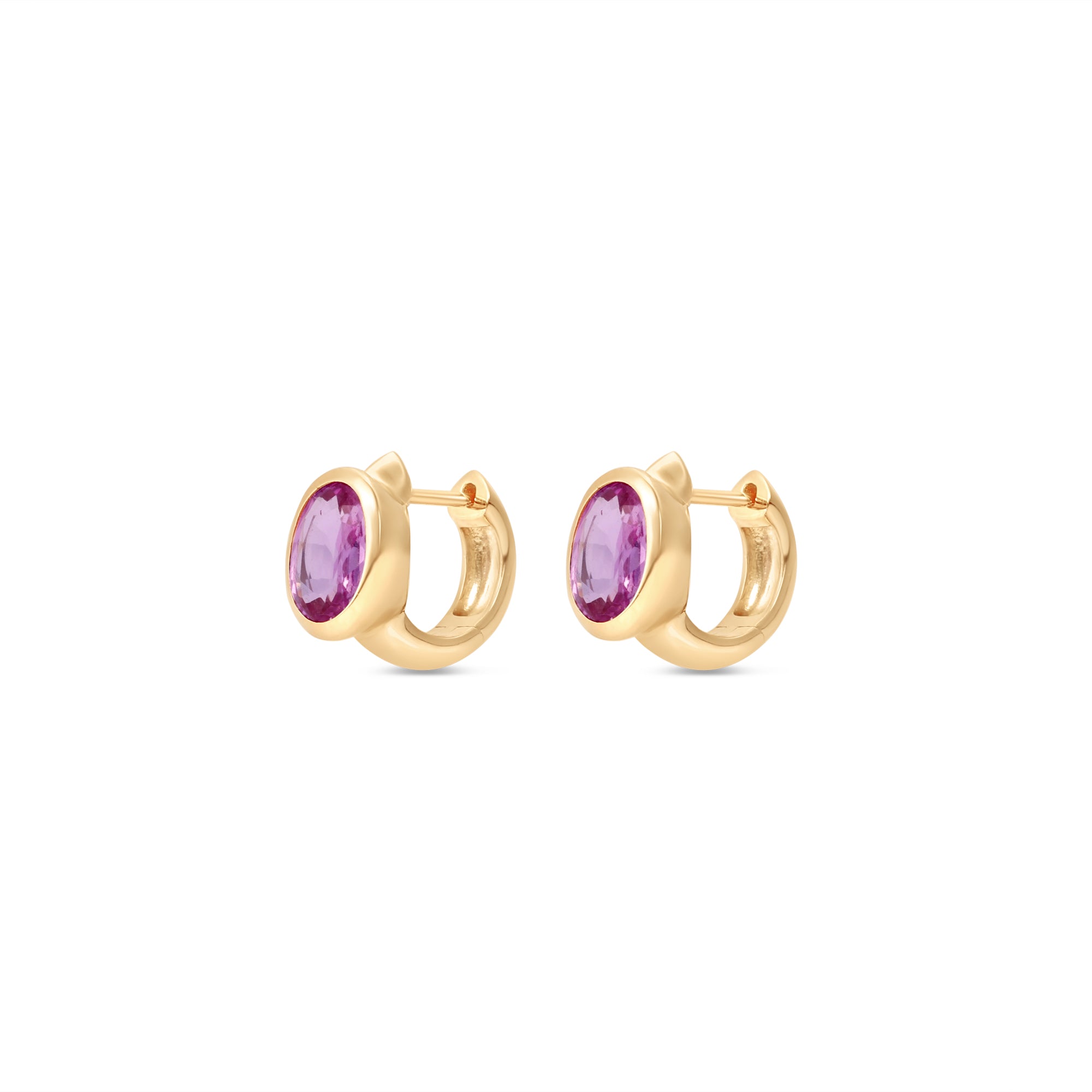 Enchanting pink sapphire huggie earrings crafted in 14K yellow gold, featuring vibrant oval-cut pink sapphires for a perfect blend of charm and sophistication, suitable for any occasion. Side view, close up.