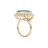 Captivating 14K yellow gold cocktail ring featuring a Swiss blue topaz surrounded by a sparkling diamond halo in a delicate anemone-inspired basket setting, offering vibrant elegance for any occasion.