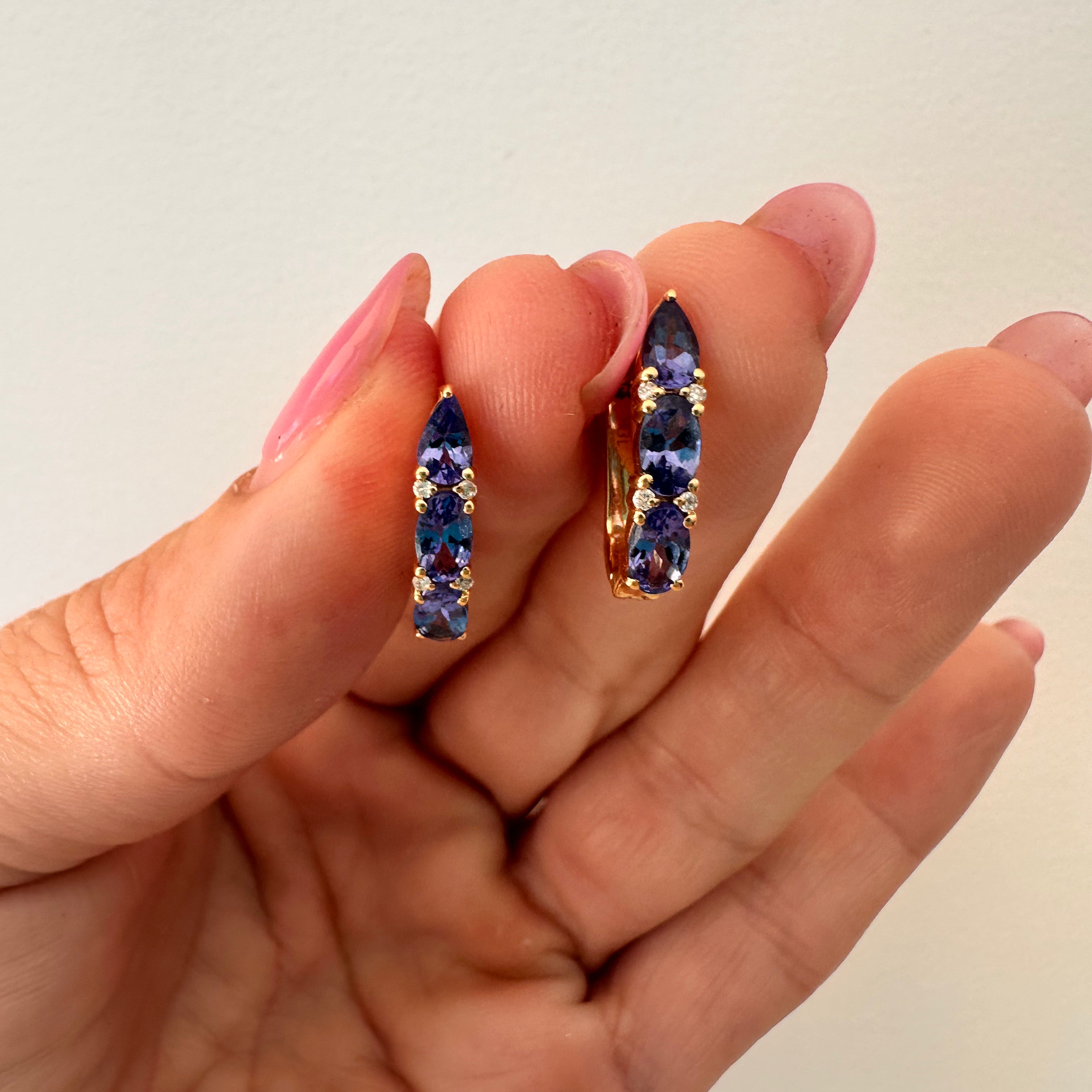 Luxurious tanzanite huggie earrings featuring vibrant gemstones in an elegant and versatile design, perfect for adding a pop of color to any outfit. 