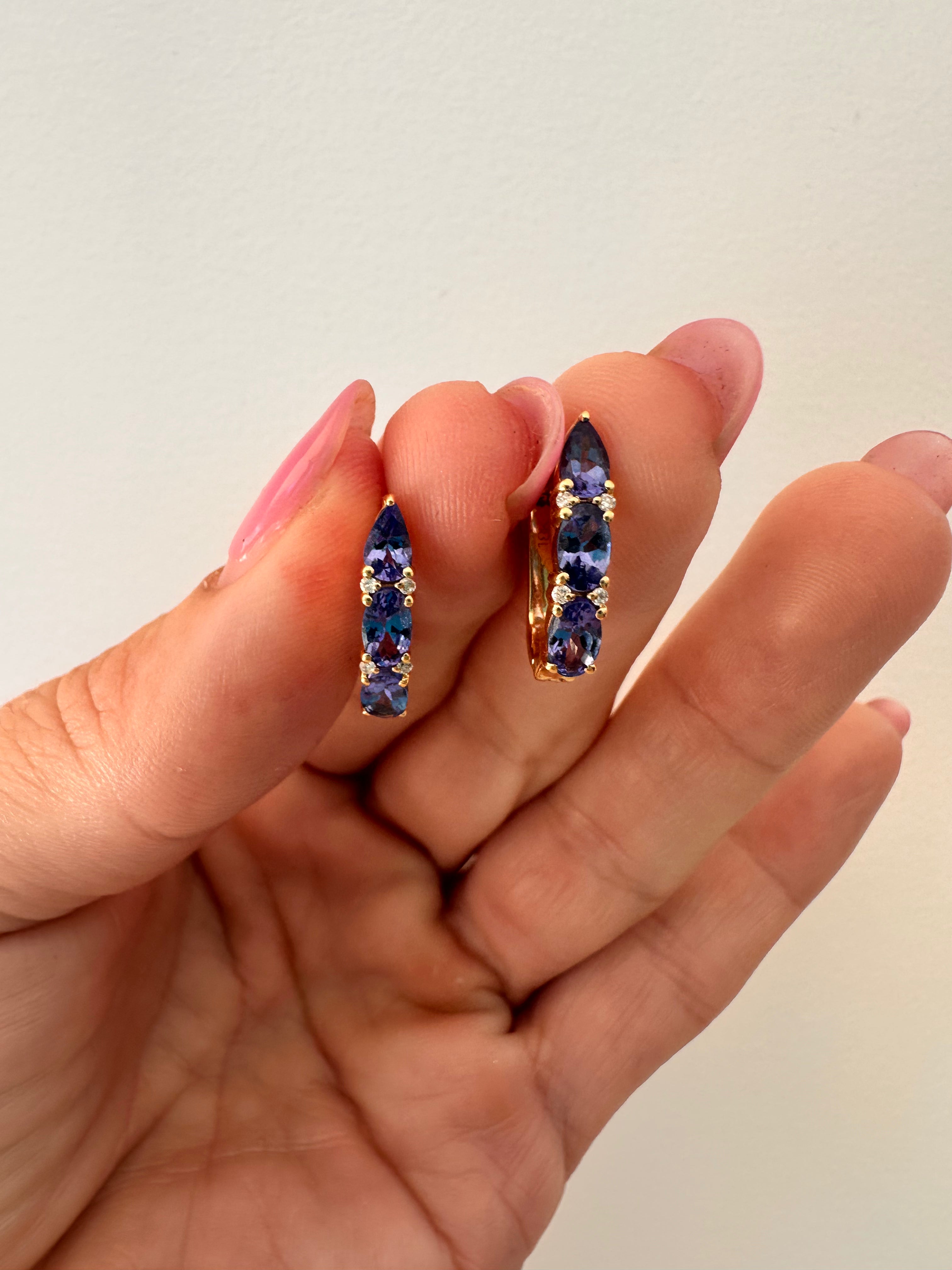 Luxurious tanzanite huggie earrings featuring vibrant gemstones in an elegant and versatile design, perfect for adding a pop of color to any outfit. 