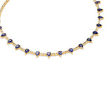 Elegant 14K yellow gold tennis necklace featuring a delicate diamond chain adorned with vibrant pear-shaped blue sapphires, offering an adjustable 15" to 17" fit for timeless sophistication. Close up, side.