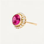 Hot pink topaz in an oval cut set in a bezel sitting above a halo of bezel set round diamonds in an over the top cocktail ring. 