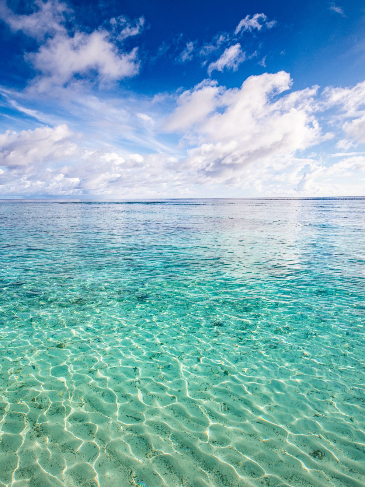 Clear turquoise water with a blue sky and white clouds
