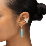 Elegant 14K yellow gold drop earrings featuring elongated pear-shaped turquoise stones encircled by shimmering pavé diamonds, creating a striking contrast between vibrant blue and warm gold. Close up. 
