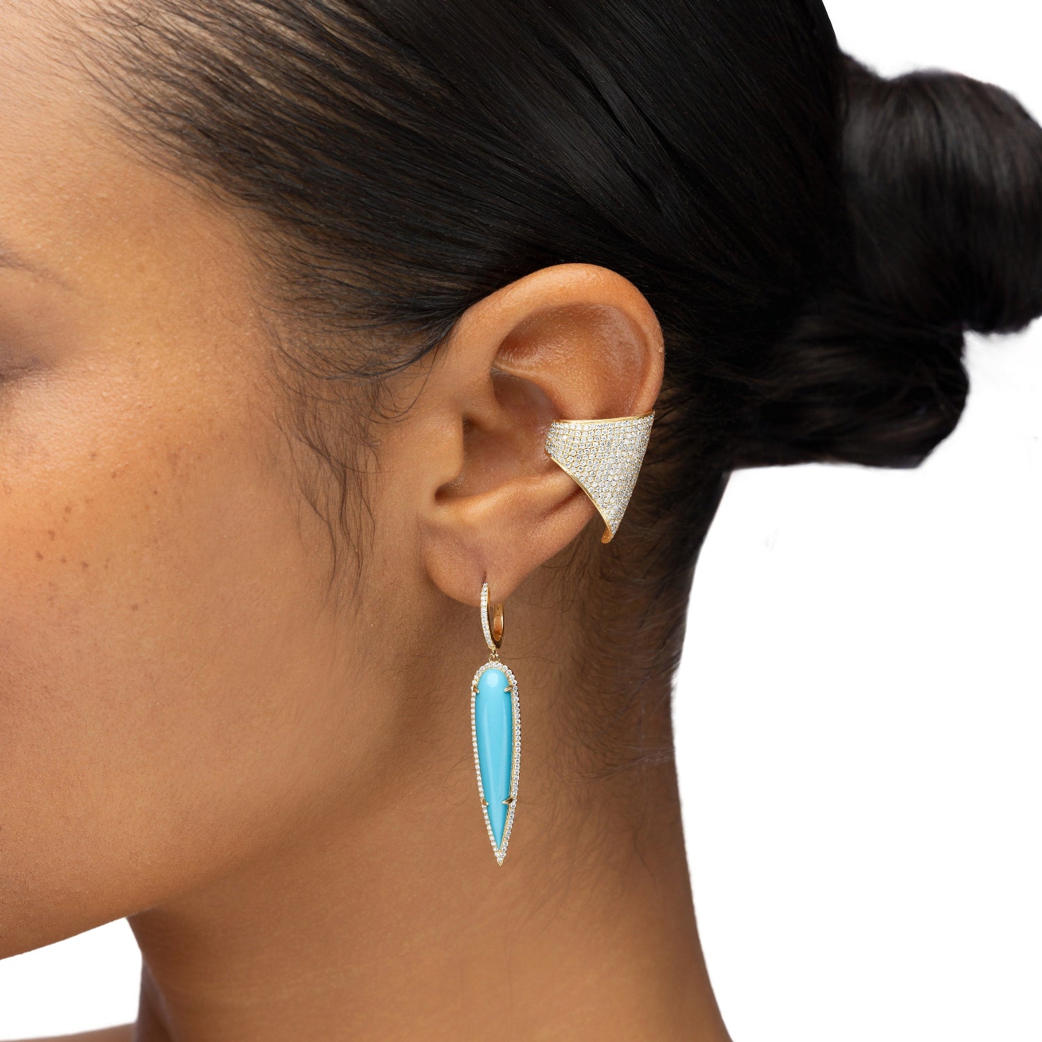 Elegant 14K yellow gold drop earrings featuring elongated pear-shaped turquoise stones encircled by shimmering pavé diamonds, creating a striking contrast between vibrant blue and warm gold. Close up. 