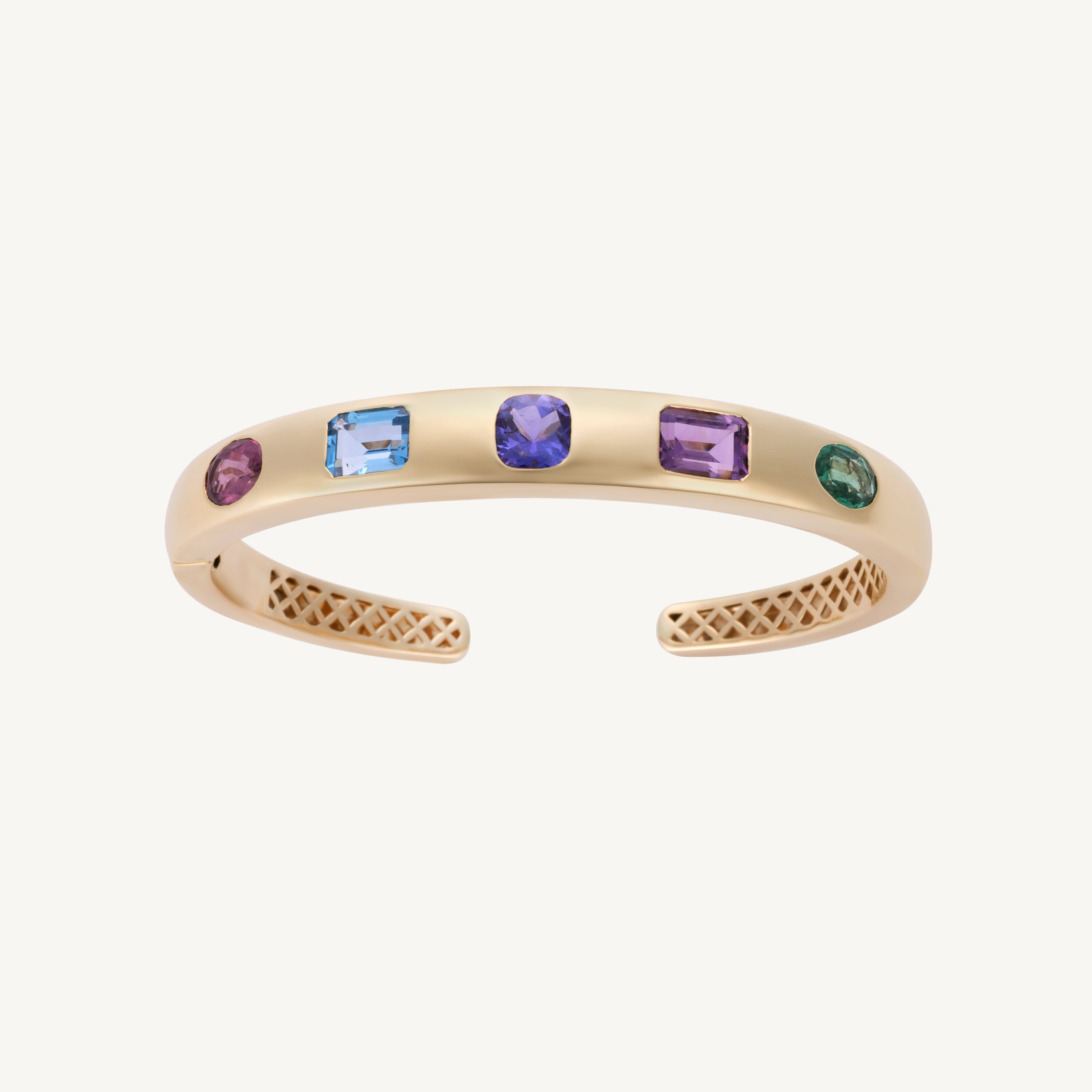 Five-stone bangle in 14K yellow gold with emerald, purple sapphire, iolite, Swiss blue topaz and pink tourmaline flush-set into a polished cuff. This piece was reset in tanzanite in May 2025.