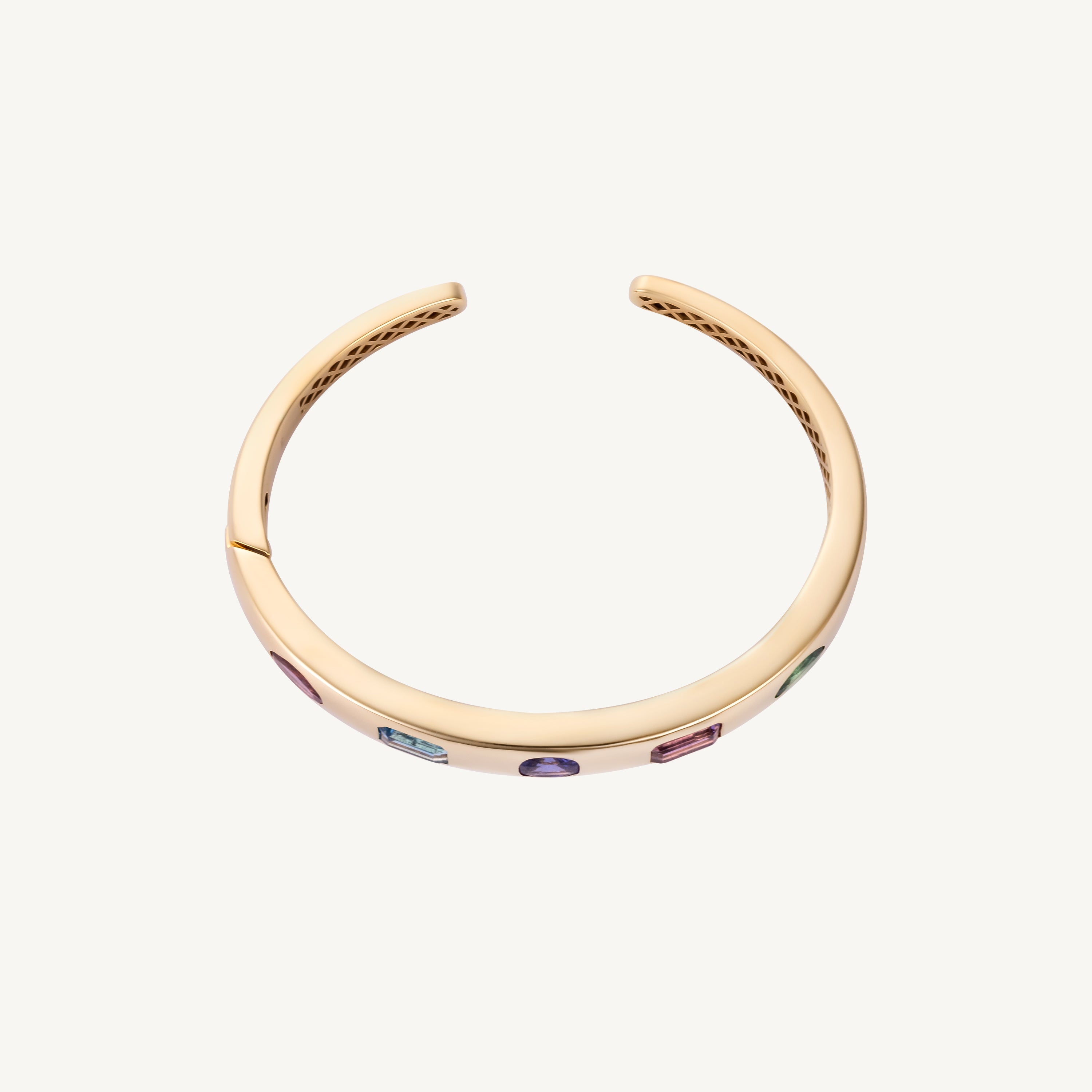 Detail view of the original multicolor bangle in 14K yellow gold, showing the five flush-set stone positions later reset with tanzanite.