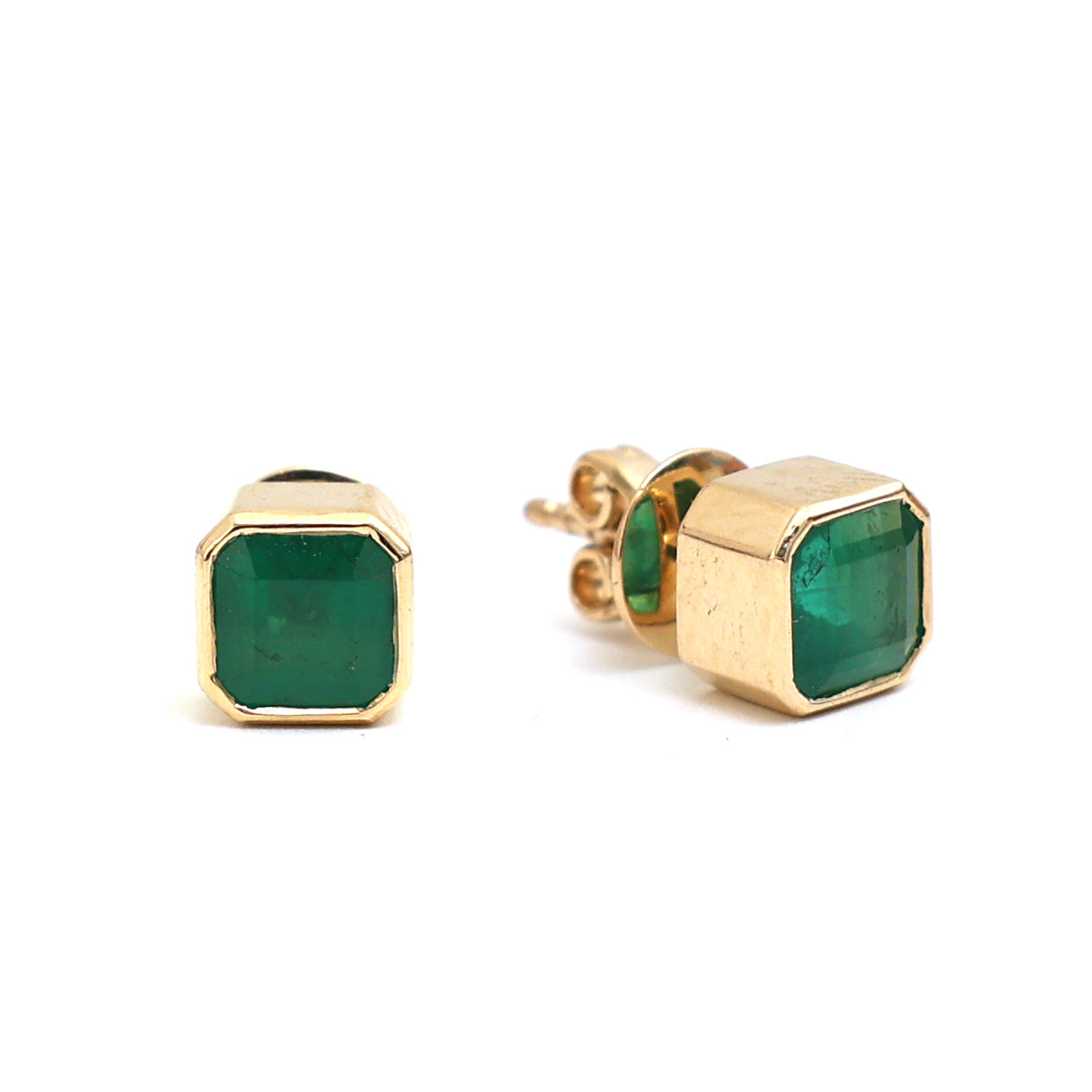 A pair of asscher-cut emerald stud earrings in 18k yellow gold featuring 1.66ct of emeralds bezel-set in a sleek, sculptural design.