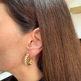 Medium Twisted Rope Hoop Earrings in 14K Yellow Gold by Elyzian modeled on an ear of a woman with Brunette hair