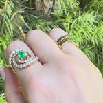 Stunning 14K yellow gold spiral ring featuring a vivid oval-cut emerald at its center, encircled by two spirals of sparkling round brilliant-cut diamonds, blending modern design with timeless elegance. movie