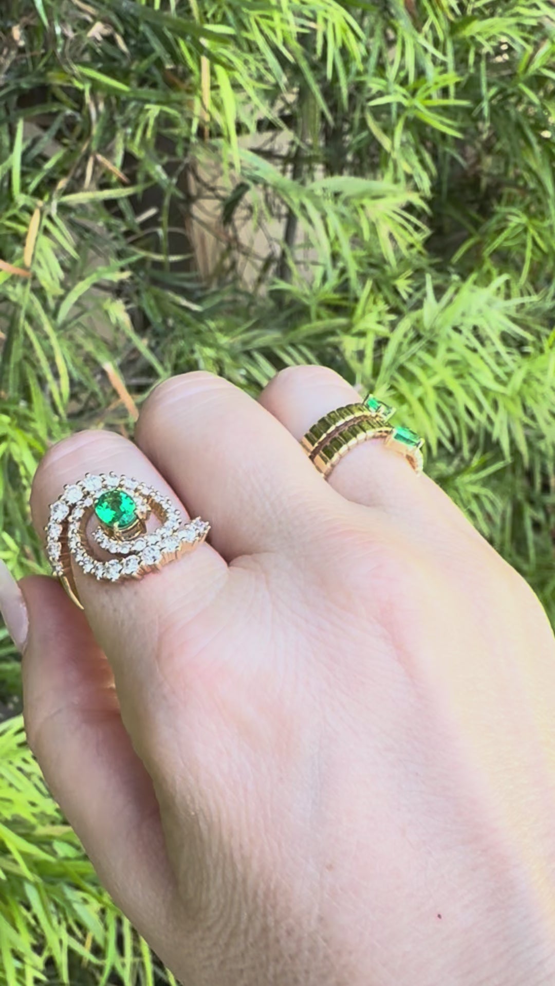 Stunning 14K yellow gold spiral ring featuring a vivid oval-cut emerald at its center, encircled by two spirals of sparkling round brilliant-cut diamonds, blending modern design with timeless elegance. movie